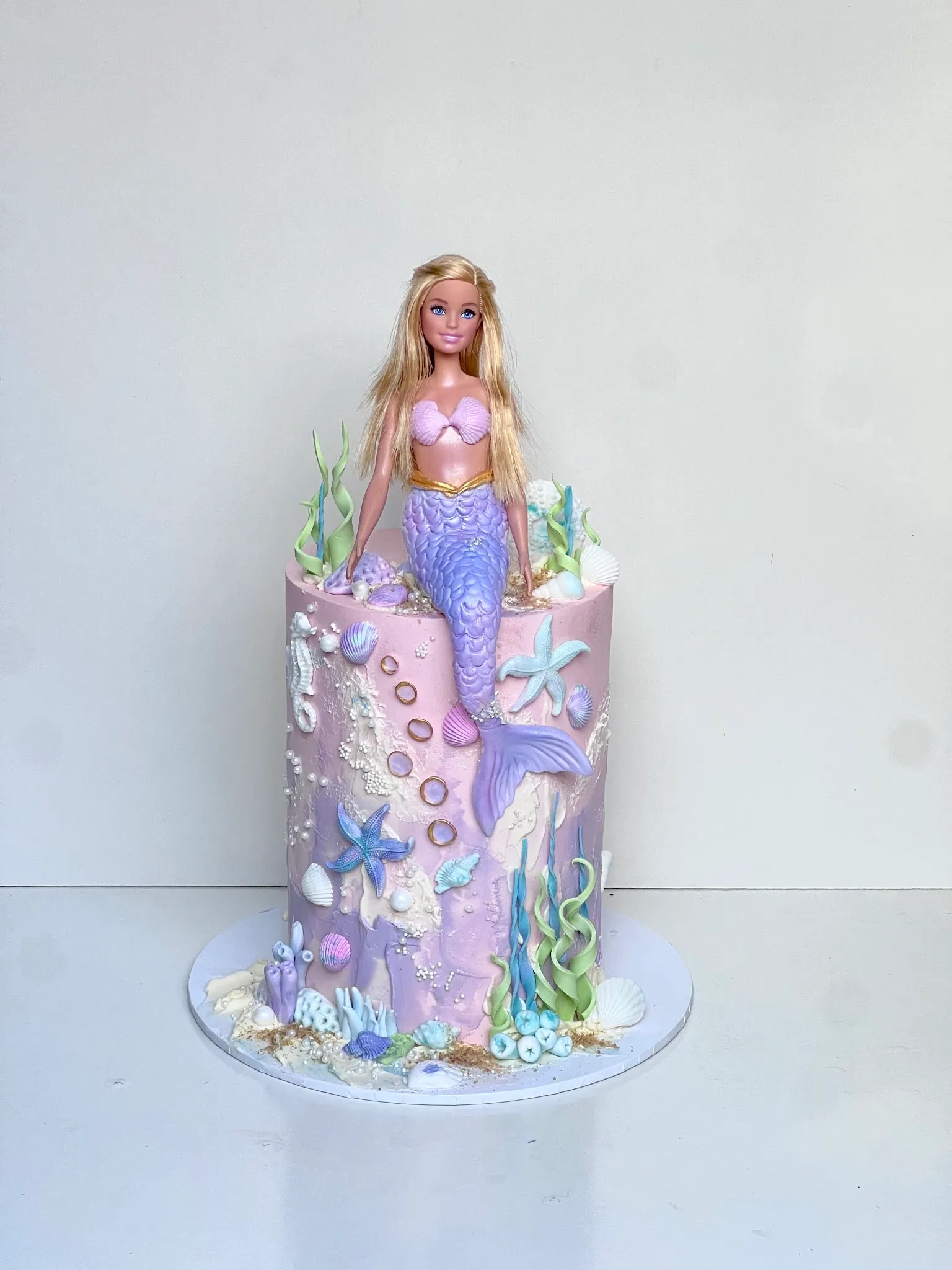 Mermaid Barbie doll birthday cake in pale pink and lavender fondant with sculpted starfish, shells and seahorse details