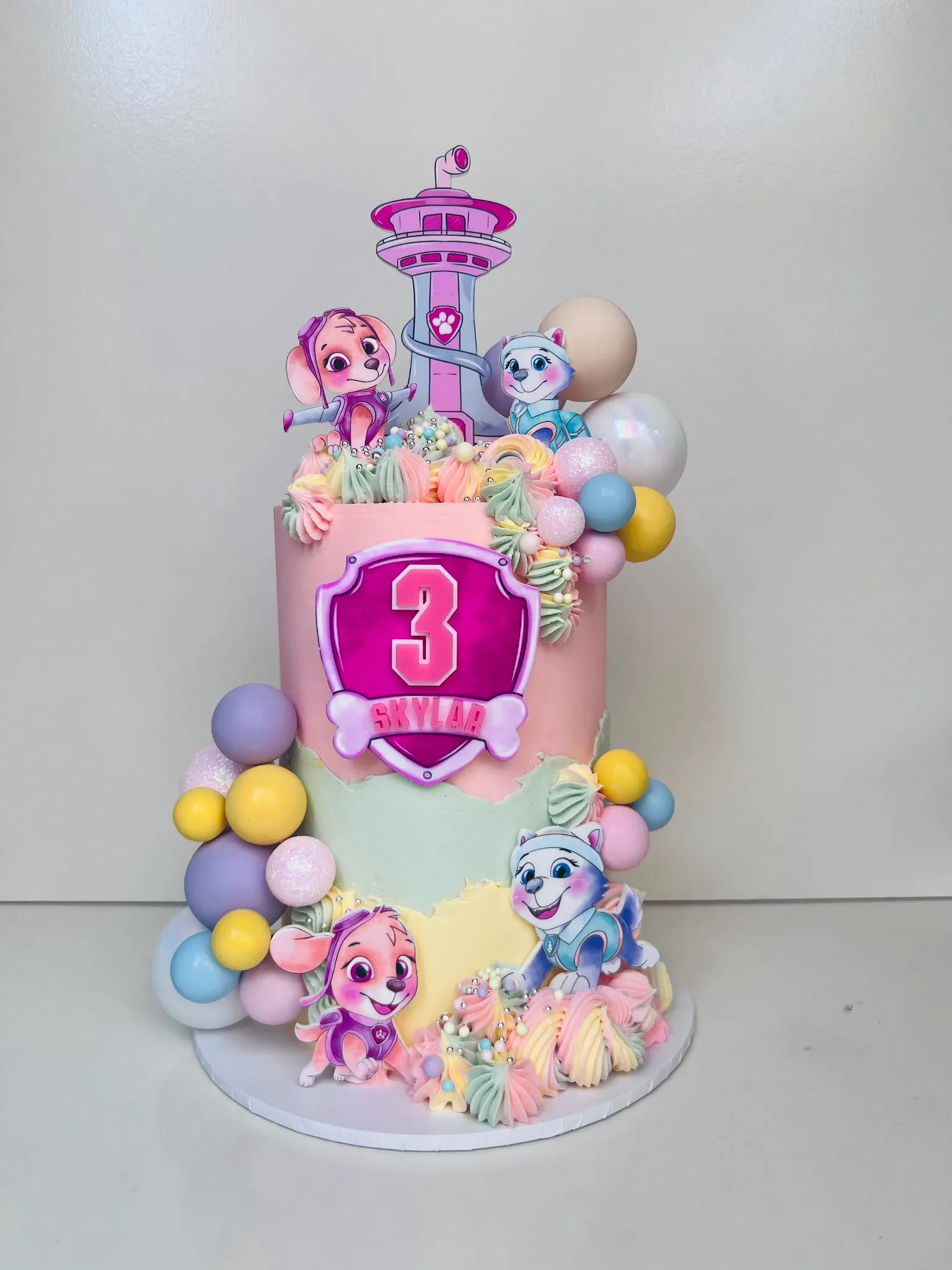 Two-tier PAW Patrol birthday cake for Skylaa's 3rd birthday in pink and mint with character standees and pastel balloons