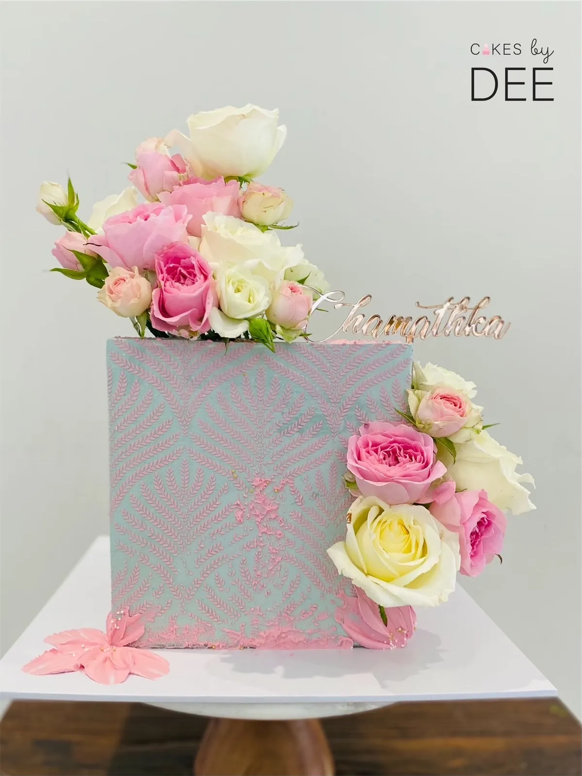 Square sage cake with pink pressed-leaf texture and cascading fresh blush roses with rose gold name plaque